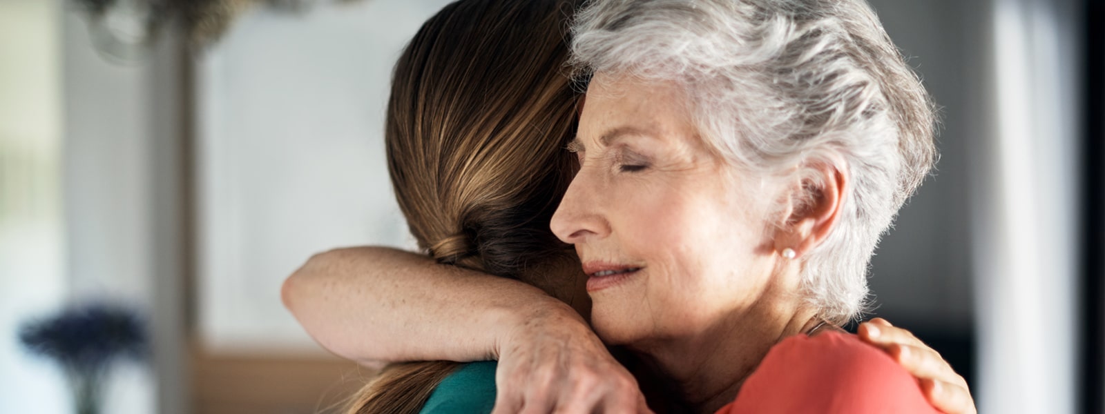 Shot of an elderly woman embracing her daughter at home