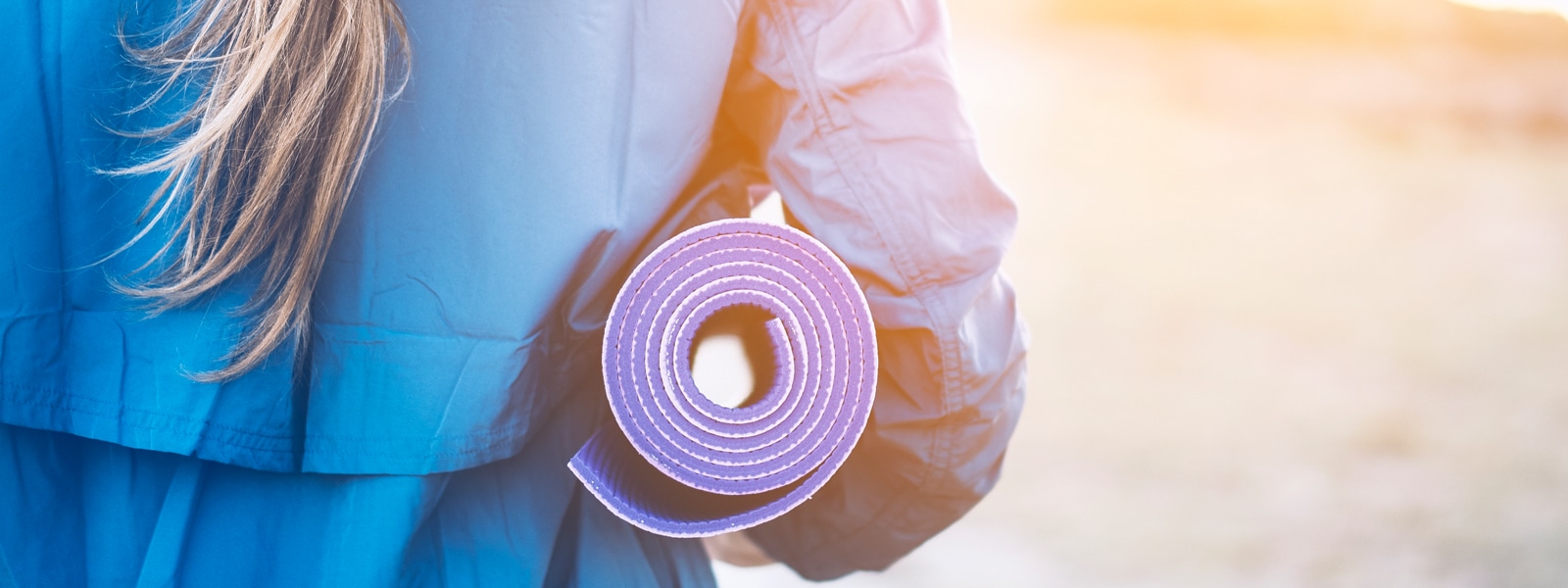 Woman holding rolled up yoga mat