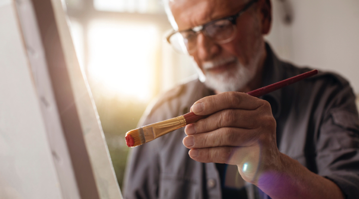 Older man painting on a canvas