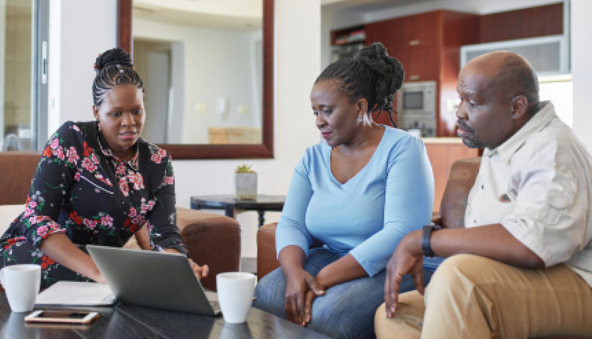 an advisor explaining something to a couple with a computer on the table