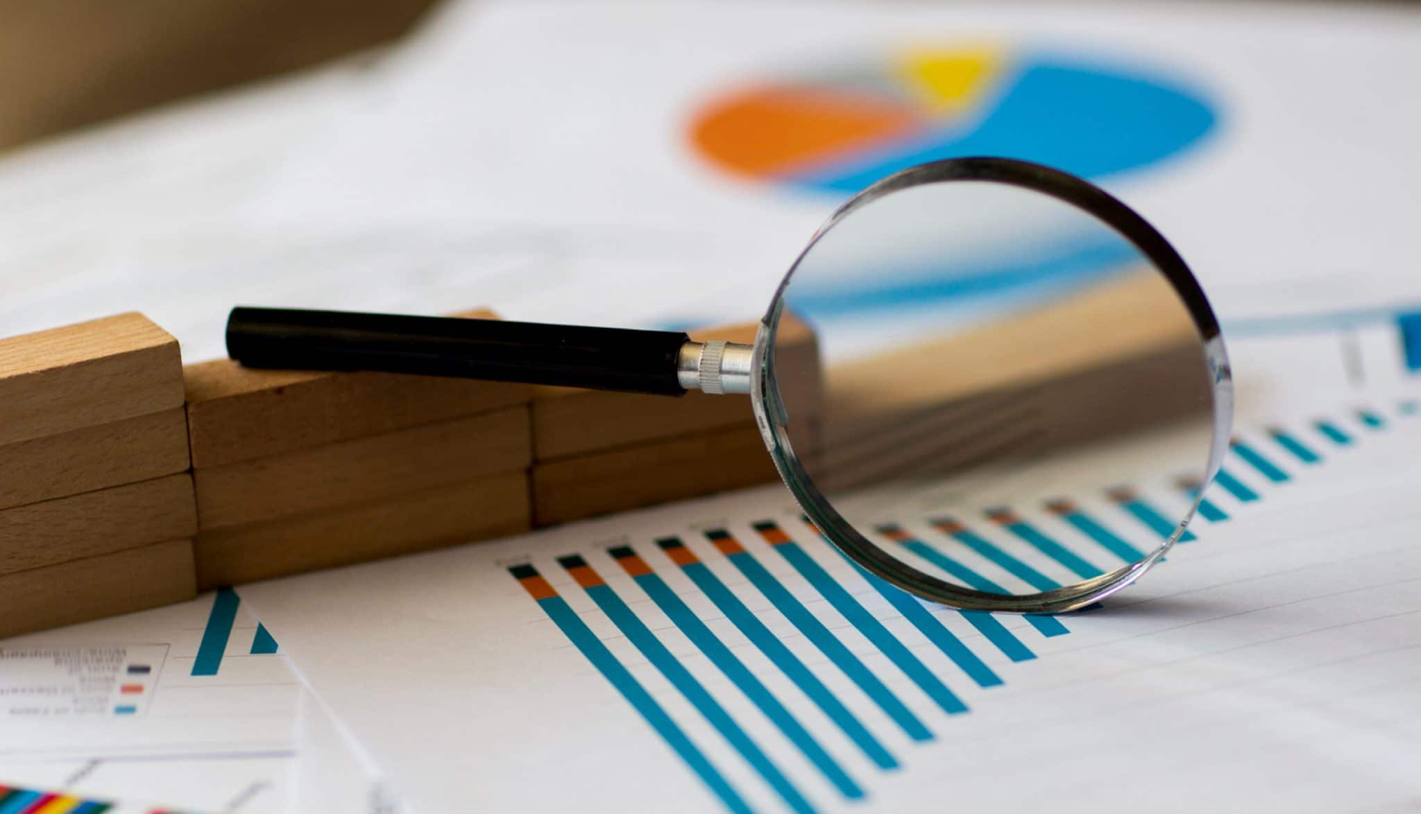 Magnifying glass over papers with charts